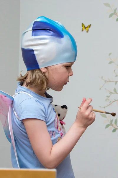 Маленькая девочка-художник с кистью в руке в резиновом колпачке — стоковое фото