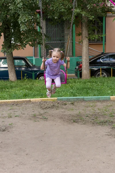 Dziewczynka z warkoczykami na huśtawce w plac zabaw dla dzieci — Zdjęcie stockowe