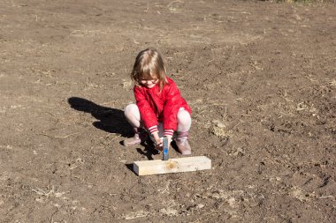 küçük kız bir tahta çivi çekiç