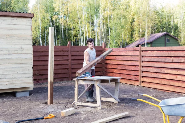 Man puts wooden beam on the bench — Stock Photo, Image