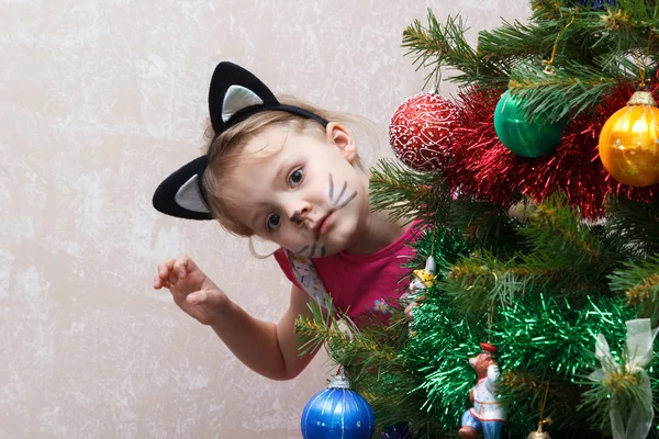 Gato pintado pequeña niña asomándose fuera de detrás de árbol de Navidad — Foto de Stock