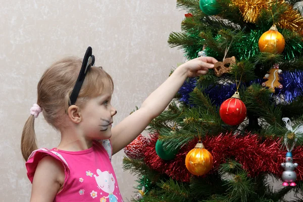 Γάτα ζωγραφισμένα κοριτσάκι διακοσμεί χριστουγεννιάτικο δέντρο με τα παιχνίδια — Φωτογραφία Αρχείου