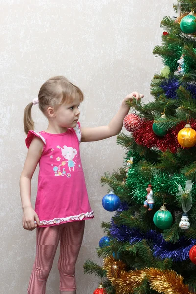 Little girl decorates Christmas tree with balls — Stock Photo, Image