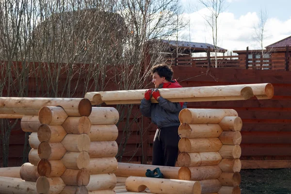 man builds structure made of logs