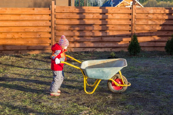 Küçük kız iterek Bahçe el arabası — Stok fotoğraf