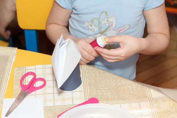 Маленькие детские руки клеят бумагу ремесла на школьном столе — стоковое фото
