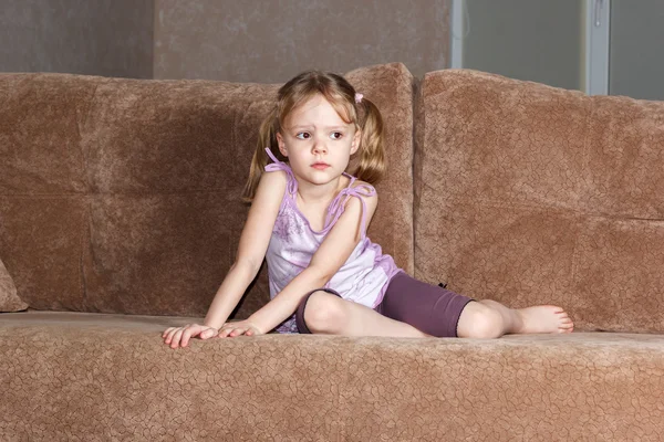 Menina pensativa com tranças sentado no sofá — Fotografia de Stock