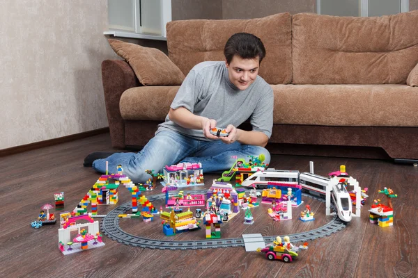Человек, играющий с городком, построенным из Lego — стоковое фото