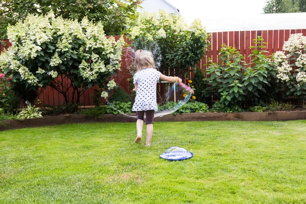 Meisje speelt met zeepbellen in prachtige tuin — Stockfoto