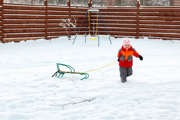 Meisje speelt met sleeën in achtertuin — Stockfoto