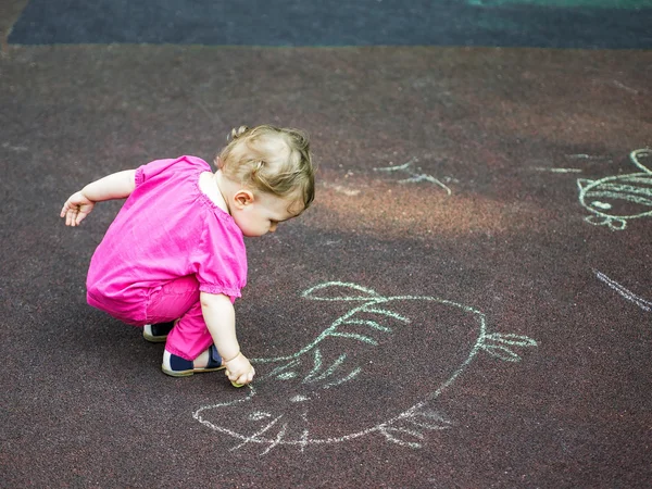 Küçük kız bir tebeşir parkta çizer..