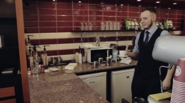 Barista vermek sıcak içecek fincan içinde bar. Genç adam al. Kahve ya da çay.
