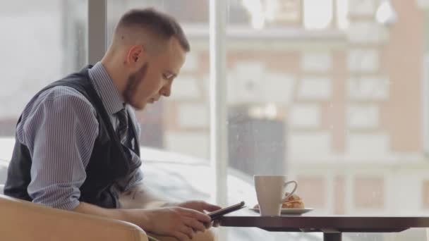 Hombre joven con Tablet PC beber café en la cafetería — Vídeos de Stock