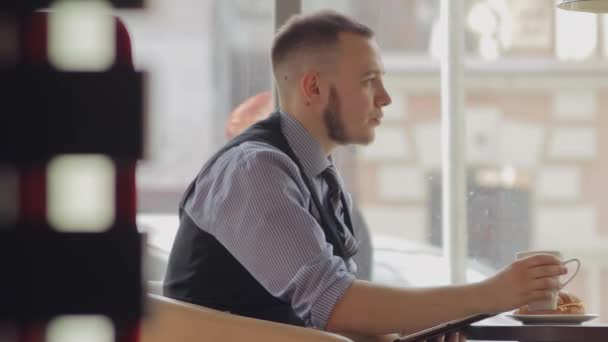 Hombre joven bebiendo café en la cafetería y el uso de tabletas — Vídeo de stock