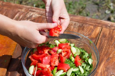 ahşap bir masa üzerinde bir tabak içinde taze sebze salatası