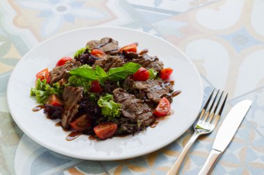 Sığır eti, domates ve marul beyaz tabakta sıcak salata