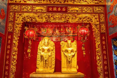 Suphanburi tapınağında kırmızı ve altın madalyalı altın tanrı heykelleri.