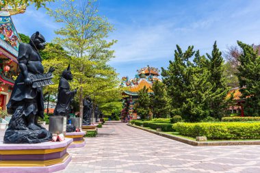 Suphan Buri Çin tapınağındaki mavi gökyüzünün altındaki bahçe yolu boyunca siyah savaşçı heykelleri.