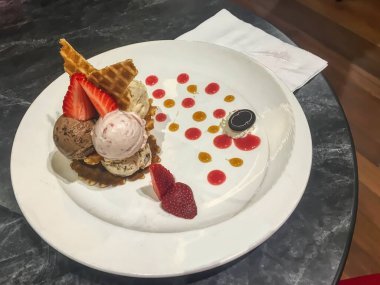 Çikolatalı ve çilekli dondurma. Meyve süslemeli waffle kasesi..