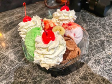 Çikolatalı, çilekli ve kirazlı dondurma ve üstüne krema ve kiraz..