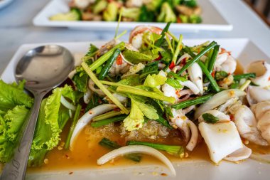 Otantik Tayland baharatlı, beyaz dikdörtgen tabakta servis edilen kalamar ve karidesli şehriye salatası..