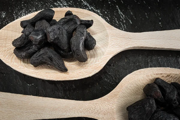 Two tablespoons with black garlic