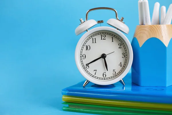 Textbooks and alarm clock on a blue background. Back to school. Library, education. Concept Education or business