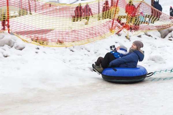 Family having fun on snow tube. mother with a kid is riding a tubing. Winter entertainment. people sliding downhill on tube