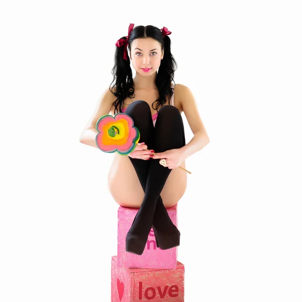 Donna sorridente erotica in bikini con grande caramella lecca-lecca seduta su scatole regalo — Foto Stock