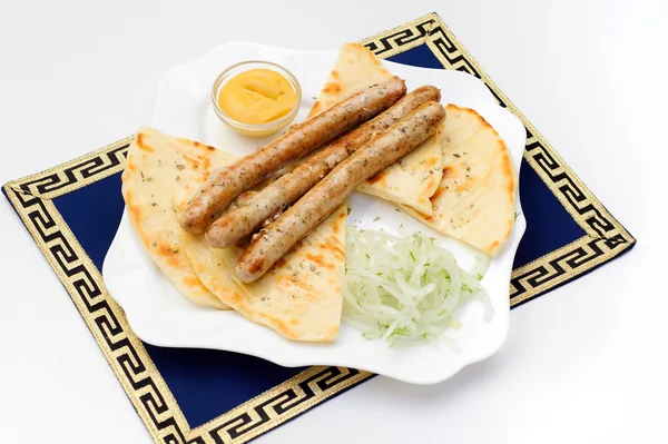 Dish with grilled sausages, pita bread, mustard and greens — Stock Photo, Image