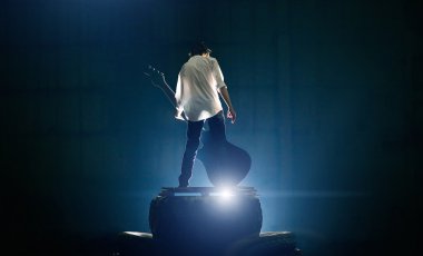 Mavi ışık altında büyük elektrik gitar oynamaktan sahnede gitarist