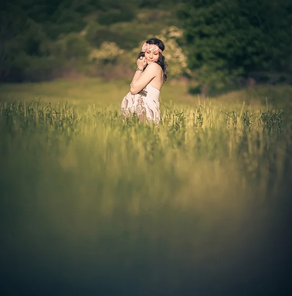 Mujer embarazada romántica fuera, en el campo y entre la vegetación como un cuento de hadas . — Foto de Stock