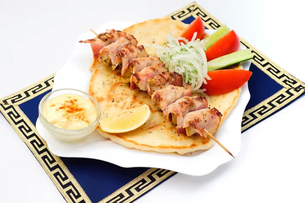 Souvlaki, kebab, grillezett húsok, pita kenyér, mártás, paradicsom és uborka, fehér lemez. — Stock Fotó