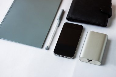 Beyaz tablo nesnelerde (telefon, cüzdan, defter, kalem, taşınabilir şarj)