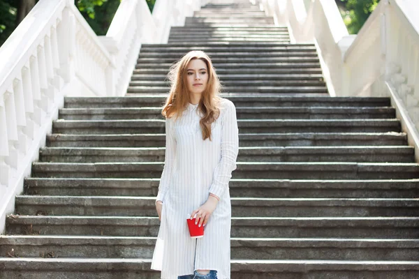 bir fincan kahve tutarak ve açık havada gülümseyen güzel kız