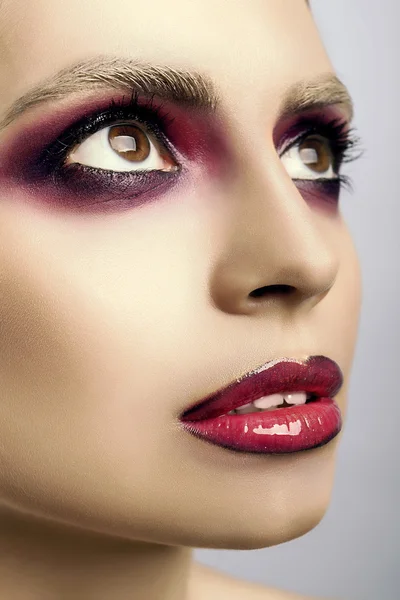 Rosto bonito com olhos e lábios cor de rosa em um fundo cinza — Fotografia de Stock