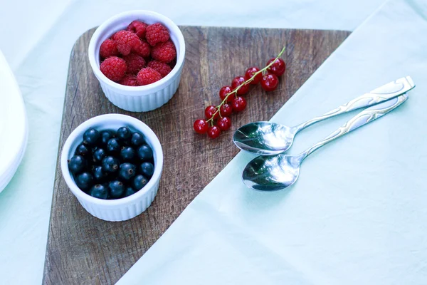 Black currant and raspberry on a wooden background — Stock Photo, Image