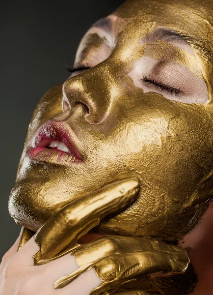 Girl with yellow paint on his face in the studio on a black back — Stock Photo, Image