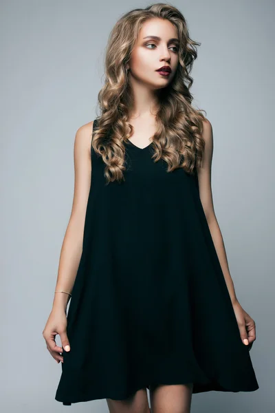 회색 배경에 측면을 찾고 검은 드레스에 아름다운 소녀. 패션 사진 — 스톡 사진