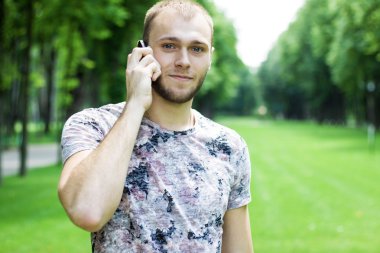 İyi görünümlü adam bahçede bir cep telefonu.