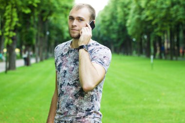 İyi görünümlü adam bahçede bir cep telefonu.