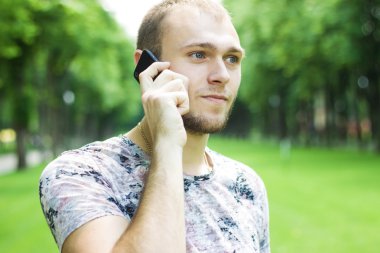 Yakışıklı adam parkta telefon ederek. El ile güzel bir adam