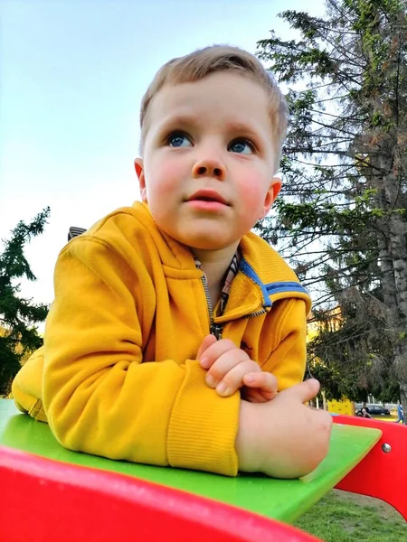 Junge in orangefarbener Jacke genießt Ausritt auf Schaukeln im Park — Stockfoto
