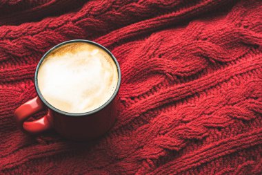 Sıcak bir kazakta kırmızı kahve fincanı..