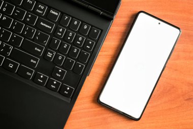 Temiz akıllı telefon ekranı. Laptop klavyesinde akıllı telefon. Çevrimiçi eğitim, iş kavramı.