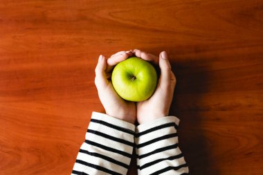 Ahşap bir arka planda kadın eli olan yeşil elma. Diyet ve sağlıklı beslenme. Ahşap arka planda bir kadın eli. Diyet ve sağlıklı yemek..