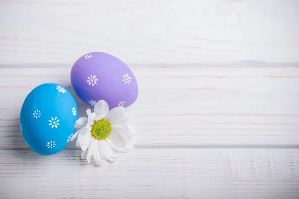 Великодні яйця з квітами на білому дерев'яному фоні — стокове фото