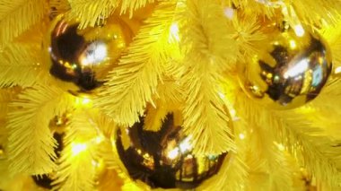 Sihirli güzel Noel ve yeni yıl geçmişi. Yapay renkli Noel ağacı, büyük altın topları ve parıldayan Noel ışıkları. Sarı yapay ladin, arkaplanı kapat