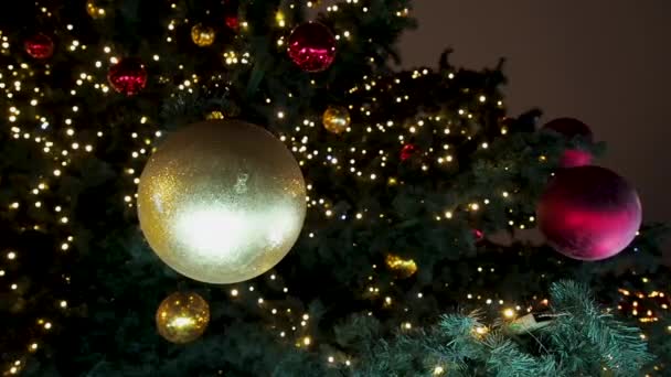 Fermez un sapin de Noël qui brille la nuit. Sapin du Nouvel An avec décorations et illumination. Décorations d'arbre de Noël fond. Beaucoup de grandes boules dorées et rouges sur sapin Nouvel An et — Video