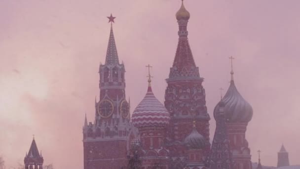 Russische Winter. Rusland, Moskou, Kathedraal van de voorspraak van de Allerheiligste Theotokos op de gracht en uitzicht op het Kremlin in een besneeuwde winteravond bij zonsondergang. De kathedraal van Vasily de gezegende in zware — Stockvideo